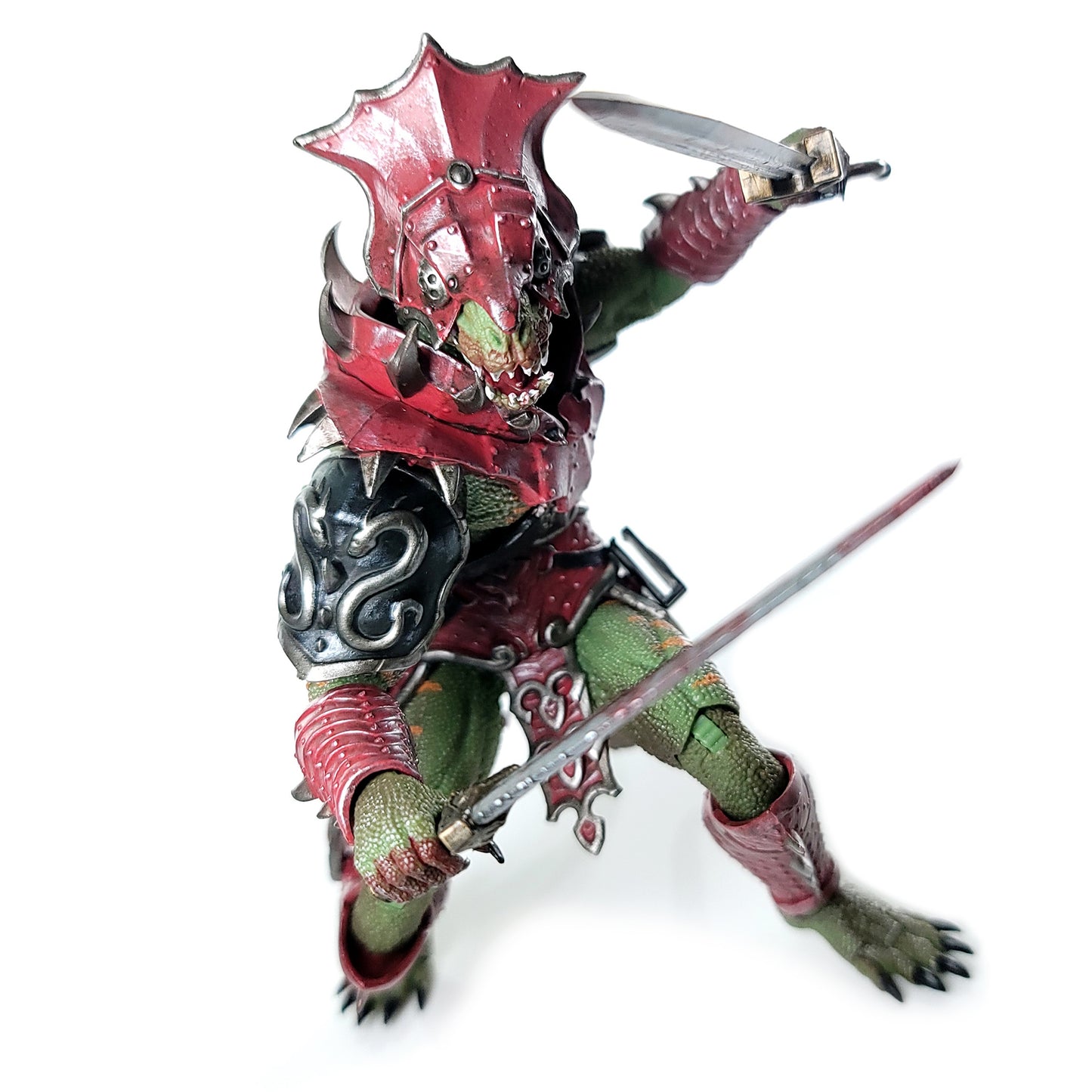 Fully armored green Lemurian with helmet lunging forward with a sword held high and pointing forward in his left hand and a sword held defensively in front in his right hand.