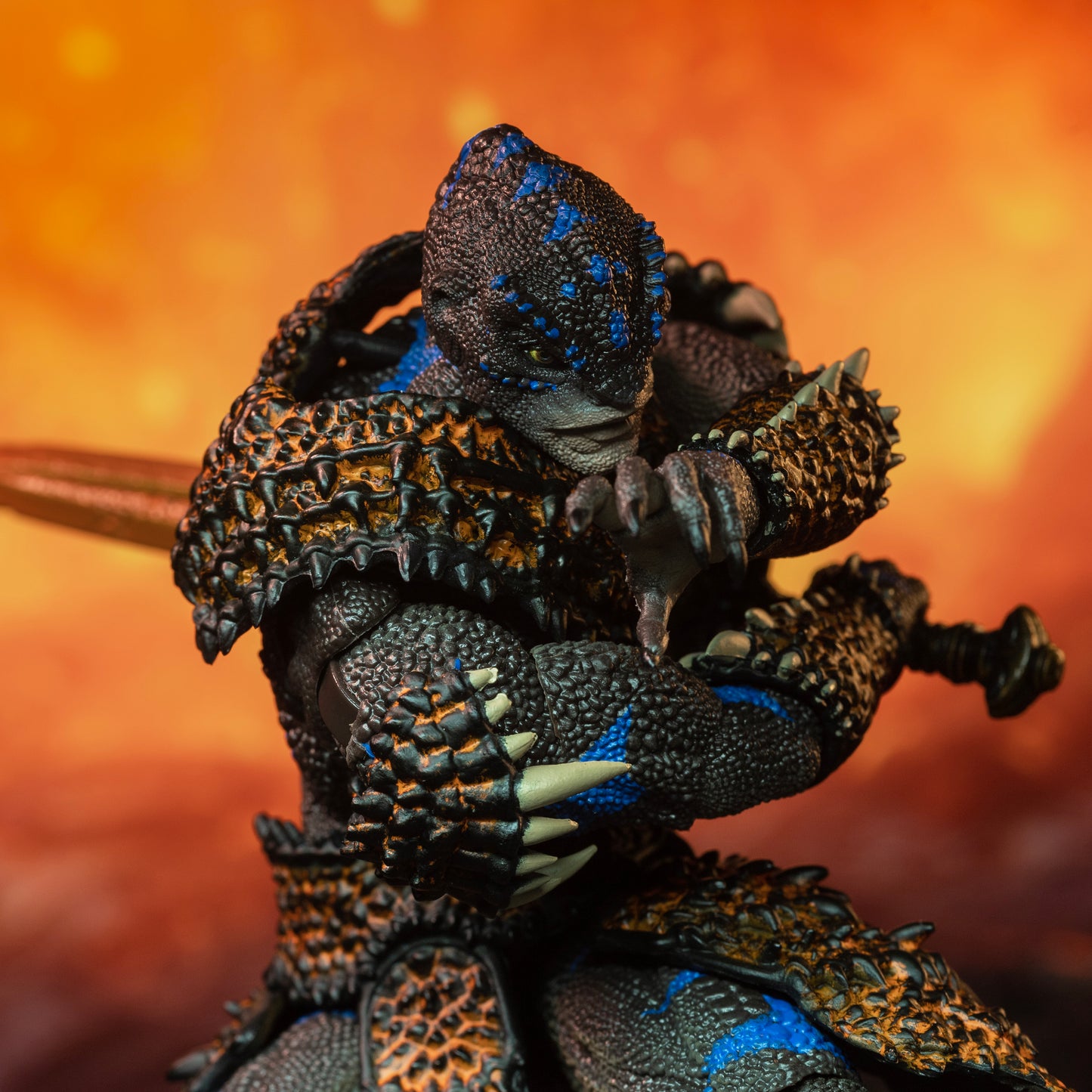 Close up of fully armored brown Lemurian with blue striping standing beside lava flow and preparing to swing his sword across his body, from left to right.