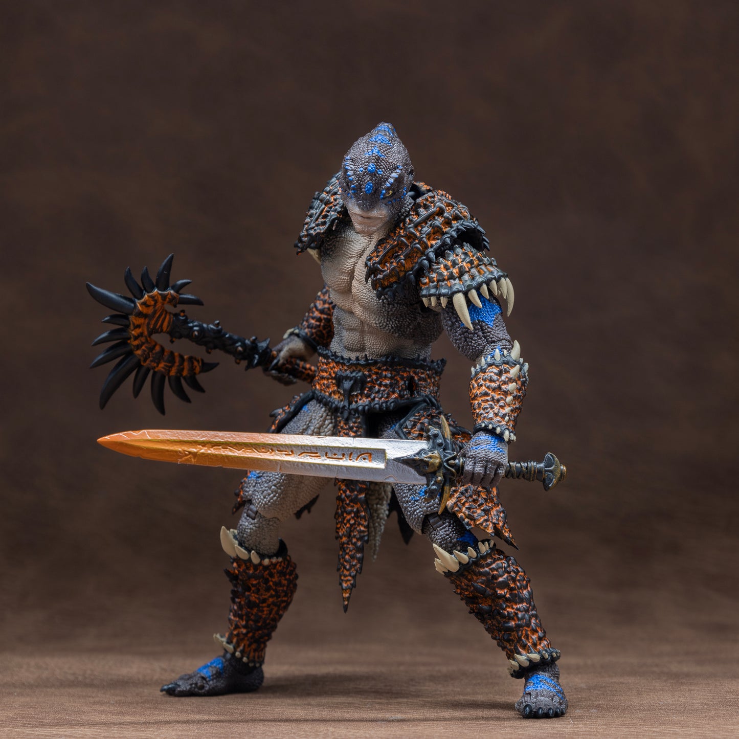 Fully armored brown Lemurian with blue striping in wide footed stance holding sword low in front of body with battle axe held at the ready behind and to the side.